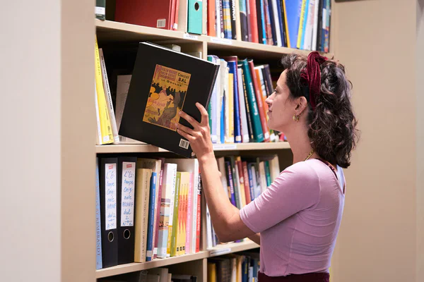 Een vrouwelijke conservator van het Van Gogh Museum pakt het boek Prints in Paris 1900 uit een boekenkast. Foto: Tomek Dersu Aaron